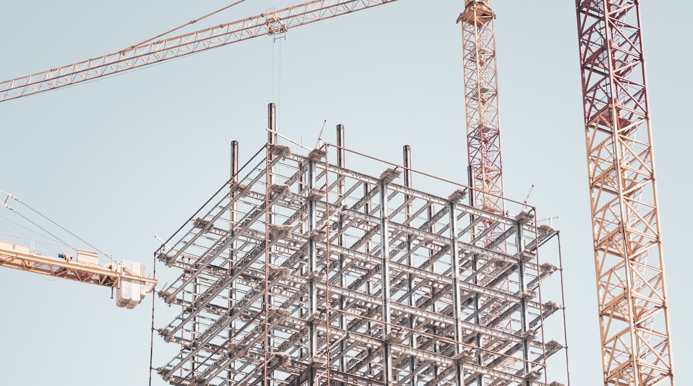 Steel-frame building under construction with tower cranes