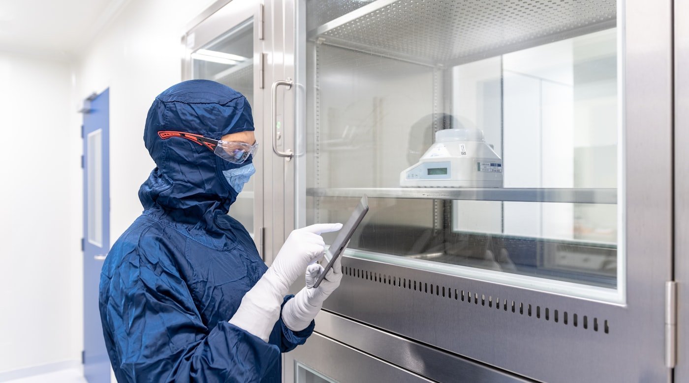 Technician in cleanroom protective suit operating pharmaceutical production equipment